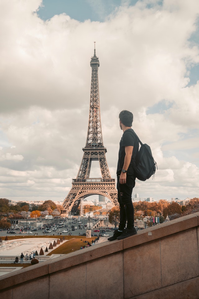 Reisender mit Rucksack geniesst Aussicht auf den Eiffelturm in Paris
