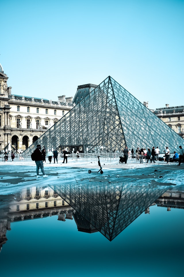 Touristen geniessen das bekannte Museum Louvre in Paris