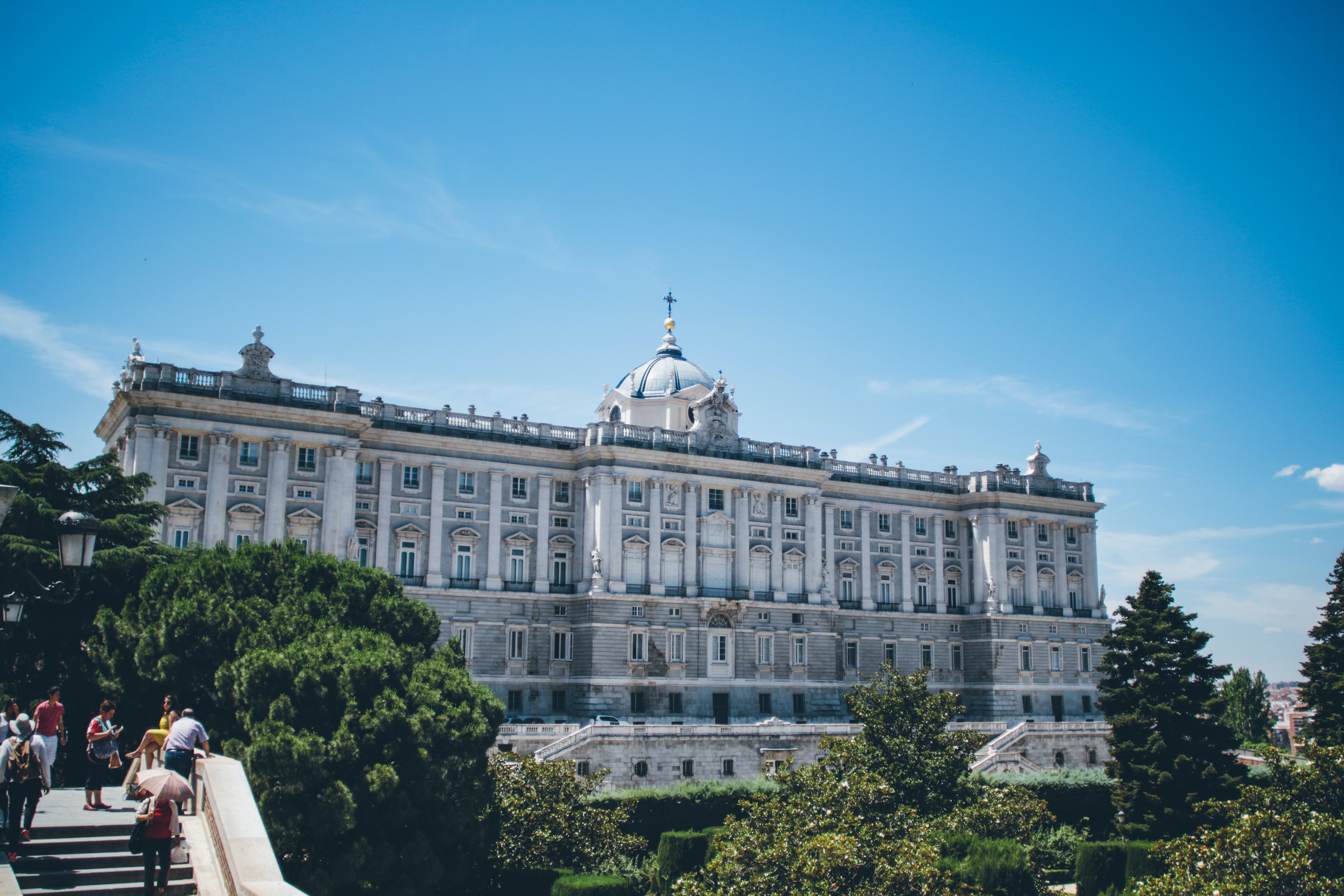 Personas caminando frente al Palacio Real de Madrid, residencia oficial del Jefe del Estado Español
